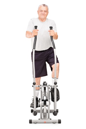 Full length portrait of a mature man excersing on a cross trainer isolated on white backgroundの写真素材
