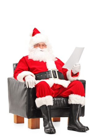 Santa Claus sitting in a comfortable armchair and reading a letter isolated on white backgroundの写真素材