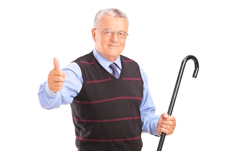 A senior man holding a cane and giving thumb up isolated on white backgroundの写真素材