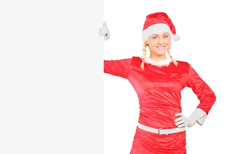 A sexy female in santa costume standing next to a blank billboardの写真素材