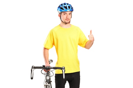 A smiling bicyclist posing next to a bicycle and giving thumb up isolated on white backgroundの写真素材