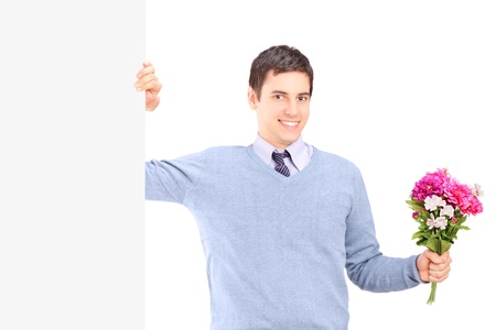 A young male holding flowers and posing next to a white panelの写真素材