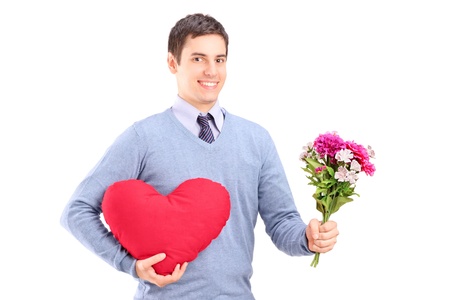 A young man holding flowers and red heart isolated on white backgroundの写真素材