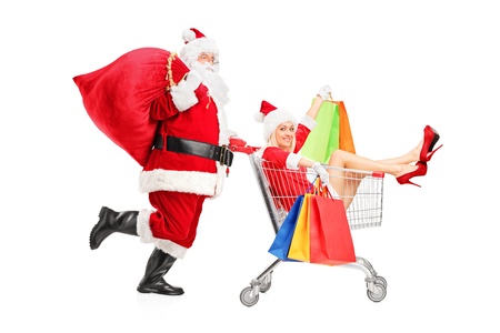 Santa Claus pushing a woman with shopping bag in a push cart isolated on white backgroundの写真素材