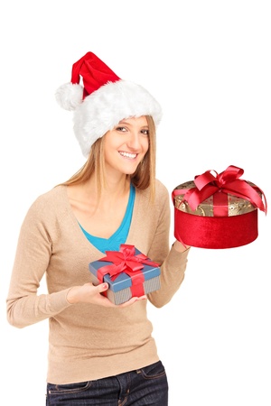 A happy female with christmas hat holding gifts in her hands isolated on white backgroundの写真素材