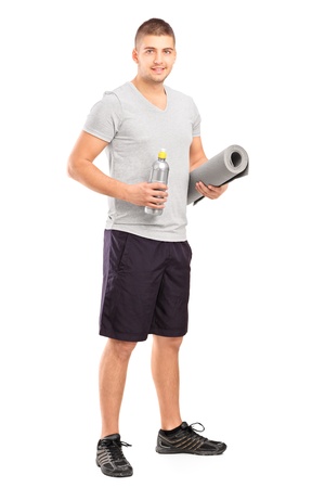 Full length portrait of a male holding a bottle of refreshment drink and a mat after an excerise isolated on whiteの写真素材
