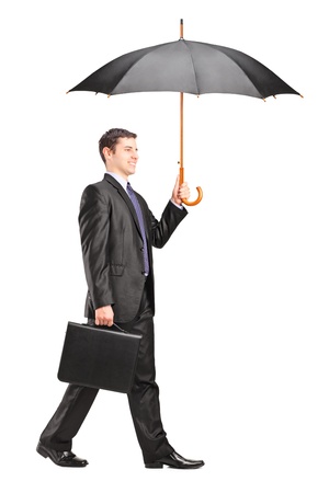 Full length portrait of a man holding an umbrella and briefcase isolated on white backgroundの写真素材