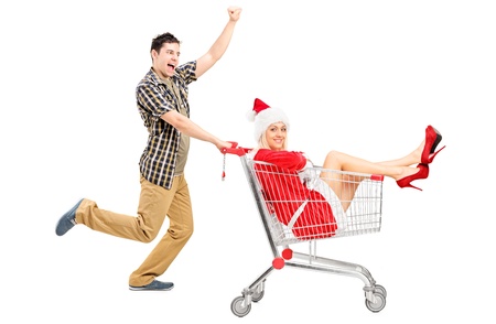 Guy pushing a woman wearing christmas costume in a shopping cart isolated on white background の写真素材