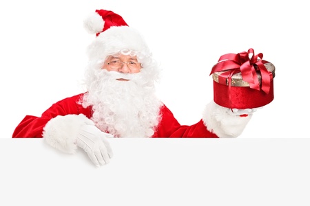 Santa Claus posing behind a blank billboard and holding a present isolated on white backgroundの写真素材