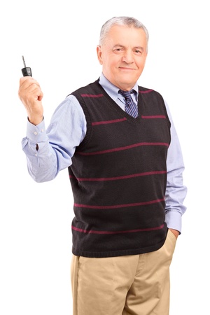 Smiling mature gentleman holding a car key isolated on white backgroundの写真素材