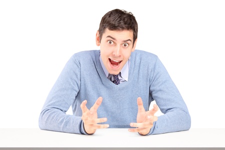 Doubtful young man sitting and gesturing with hands isolated on white backgroundの写真素材