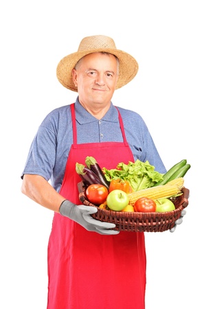 Mature farmer man holding a basket with fresh vegetables isolated on white backgroundの写真素材