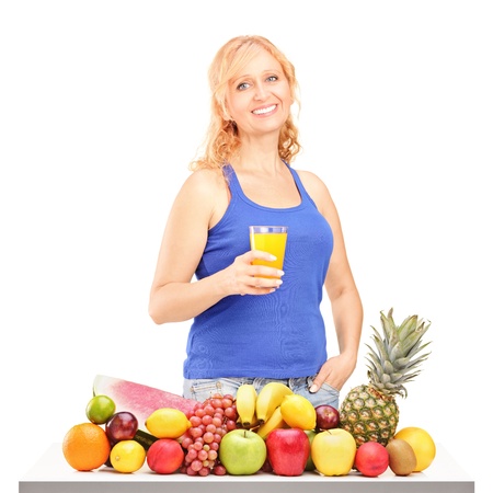 Woman holding glass of orange juice in front of pile of fruit isolated on white backgroundの写真素材