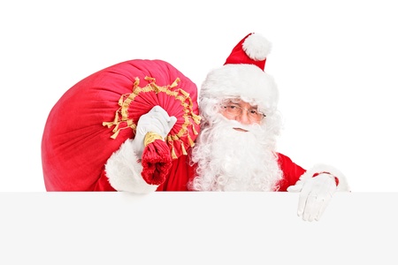 Santa Claus carrying a bag and posing behind a blank billboard isolated on white backgroundの写真素材