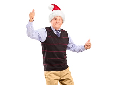 A happy mature gentleman with christmas hat giving thumbs up isolated on white backgroundの写真素材