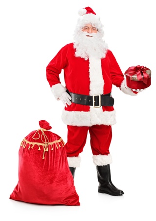 Full length portrait of a Santa Claus holding a gift and bag full of presents next to him isolated on white backgroundの写真素材