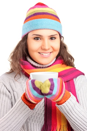 A smiling female wearing a hat and scarf and holding a cup of tea isolated on white backgroundの写真素材
