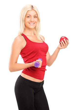 Attractive athlete female holding a dumbbell and red apple isolated on white backgroundの写真素材
