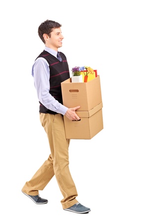 Full length portrait of a smiling male walking with boxes, moving into a new home isolated on white backgroundの写真素材