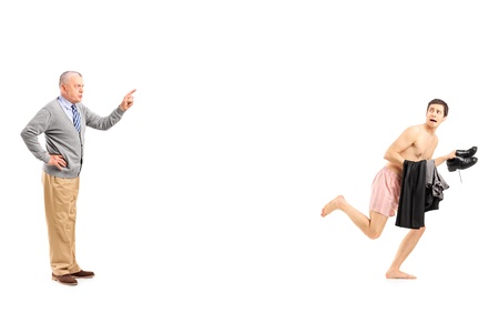 Full length portrait of a mature man shouting at a young naked man running away, isolated on white backgroundの写真素材