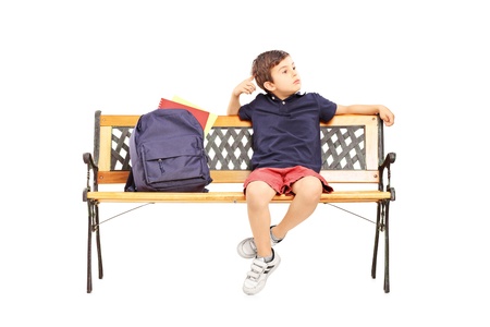 Schoolboy in thoughts sitting on a wooden chair isolated on white backgroundの写真素材