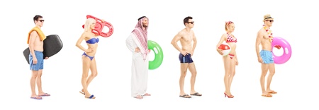 Full length portrait of young people with summer objects waiting in line isolated on white background, shot with a tilt and shift lensの写真素材