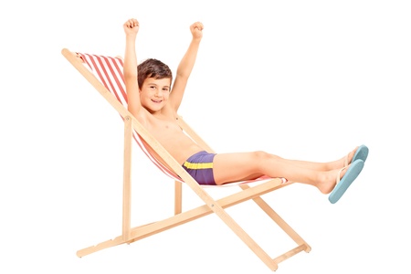 Happy boy sitting on an outdoor chair with raised hands isolated on white backgroundの写真素材