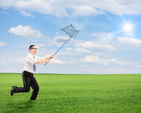 Young male running with empty butterfly net on a fieldの写真素材