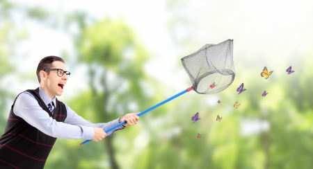 Young male catching butterflies with net in a parkの写真素材
