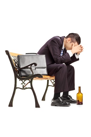 Disappointed young businessperson sitting on a wooden bench isolated on white backgroundの写真素材
