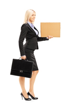 Full length portrait of a young woman in black suit holding a piece of cardboard isolated on white backgroundの写真素材