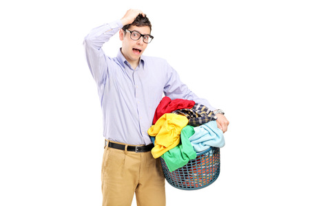 Young man holding a laundry basket and gesturing isolated on white backgroundの写真素材