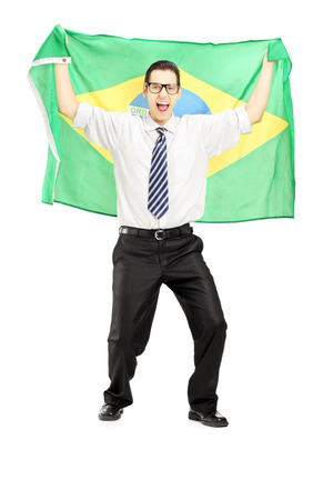 Full length portrait of an excited male holding a brazilian flag isolated on white backgroundの写真素材