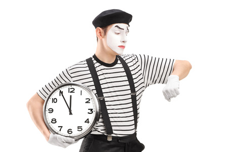 Mime artist holding a clock and checking the time, isolated on white backgroundの写真素材