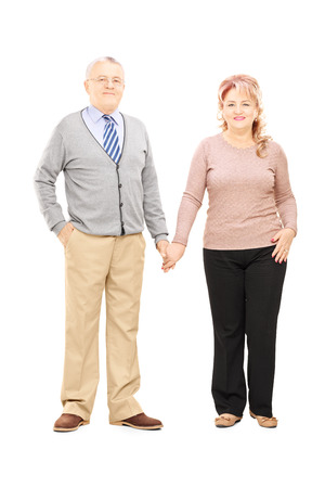 Full length portrait of a middle aged couple holding hands and posing isolated on whiteの写真素材