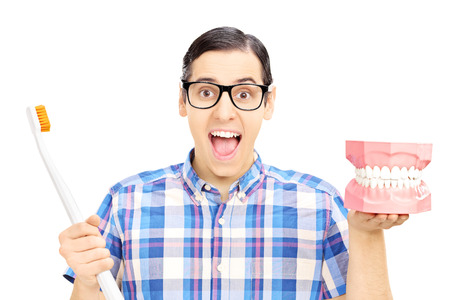 Guy holding a dentures made out of plaster cast and toothbrush isolated on white