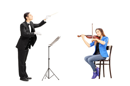 Male orchestra conductor directing a female playing violin isolated against white backgroundの写真素材