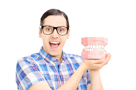 Guy holding dentures made out of plaster cast and looking at camera, isolated on white background