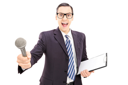 Excited young male interviewer in suit holding microphone, isolated on white backgroundの写真素材