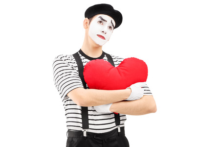 Thoughtful mime artist holding a red heart isolated on white backgroundの写真素材