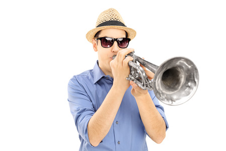 Young male musician with sunglasses blowing into trumpet, isolated on white backgroundの写真素材