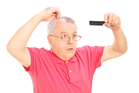 Surprised mature man holding a comb isolated on white backgroundの写真素材