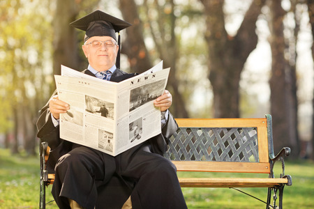 Mature college professor reading newspaper outdoorsの写真素材