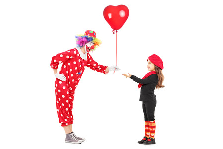 Male clown giving a red balloon to a little girl isolated on white backgroundの写真素材