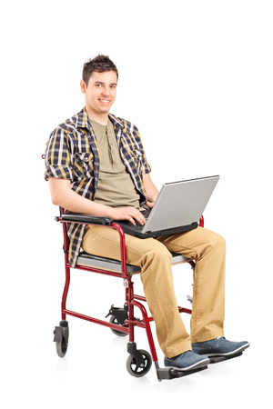 Young man in wheelchair working on a laptop isolatedの写真素材