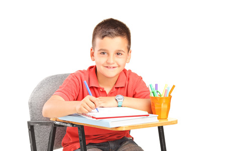 Little boy writing in a notebook isolated on white backgroundの写真素材