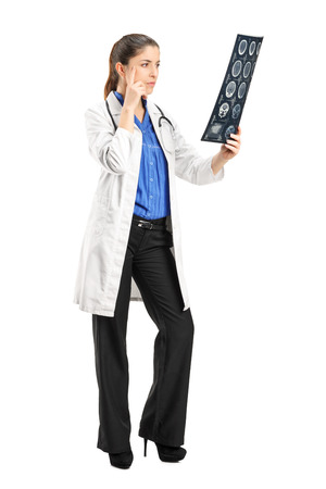 Full length portrait of a female doctor analyzing an x-ray isolated on white backgroundの写真素材