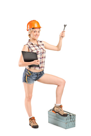 Full length portrait of a female mechanic holding a wrench and stepping onto a toolbox isolated on white backgroundの写真素材