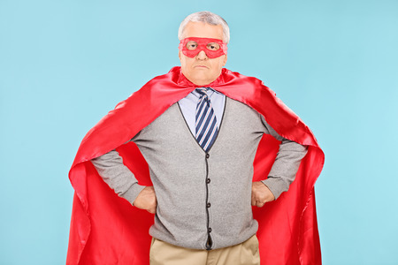 Mature superhero with red cape on blue backgroundの写真素材