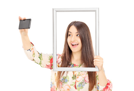 Woman taking a selfie behind a picture frame isolated on white background